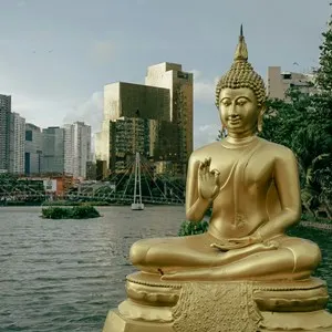 a golden buddha statue sitting in front of a body of water in Colombo, Sri Lanka