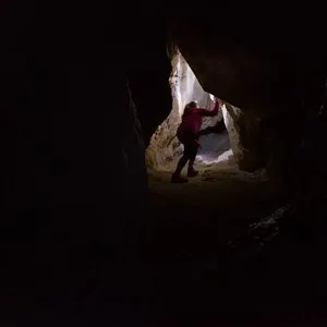 Woman Caver Spelunker exploring inside of a Dark Cave
