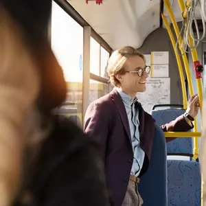 Selective focus of young man in eyeglasses riding in city bus