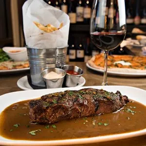 Steak au Poivre served with a side of french fries and red wine.