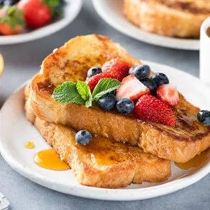 French toast with fresh berries and sweet syrup on plate served with espresso coffee