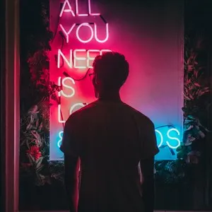 man standing in front of a neon sign