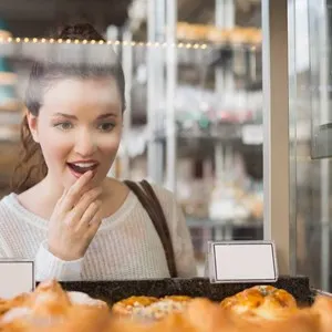 Pretty brunette looking at pastrys at the bakery