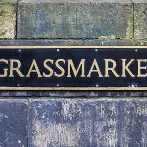 A direction sign pointing towards Grassmarket in Edinburgh, Scotland.