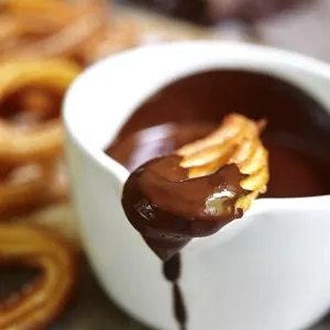 Traditional mexican dessert churros with chocolate sauce on a rustic background.