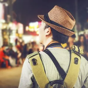Young male backpacker walking in a famous street night market in Asia (Grainy Vintage Tone and Soft Focus)