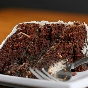 A slice of rich moist chocolate cake on a white plate with layers